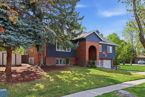 View of front of property featuring brick siding, a front yard, an attached garage.