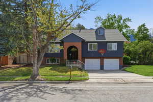 Raised ranch with a front lawn, brick siding, concrete driveway, an attached garage, and roof with shingles