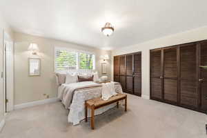 Large Primary bedroom with multiple closets and light carpet