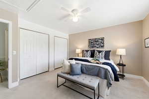 Bedroom featuring multiple closets, light carpet, and ceiling fan