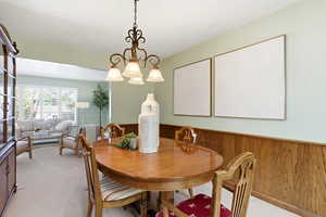 Dining room with a wainscoted wall, light carpet, and wooden walls