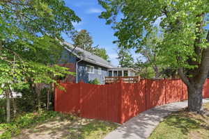 View of the side of the home with a fenced front yard and brick siding. The backyard backs to a quiet cul-de-sac, offering unobstructed mountain views and convenient additional guest parking.
