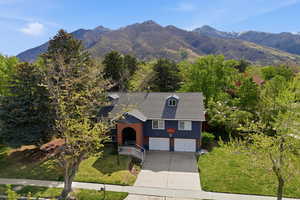 View of front of house with a front lawn, concrete driveway, a mountain view, an attached garage, and brick siding