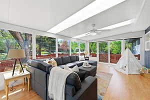 Sunroom / solarium featuring wood finished floors, vaulted ceiling, and a skylight