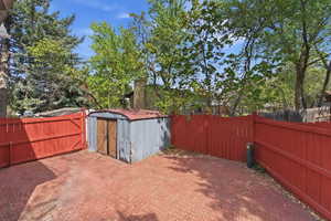 Fenced backyard with multiple storage sheds.