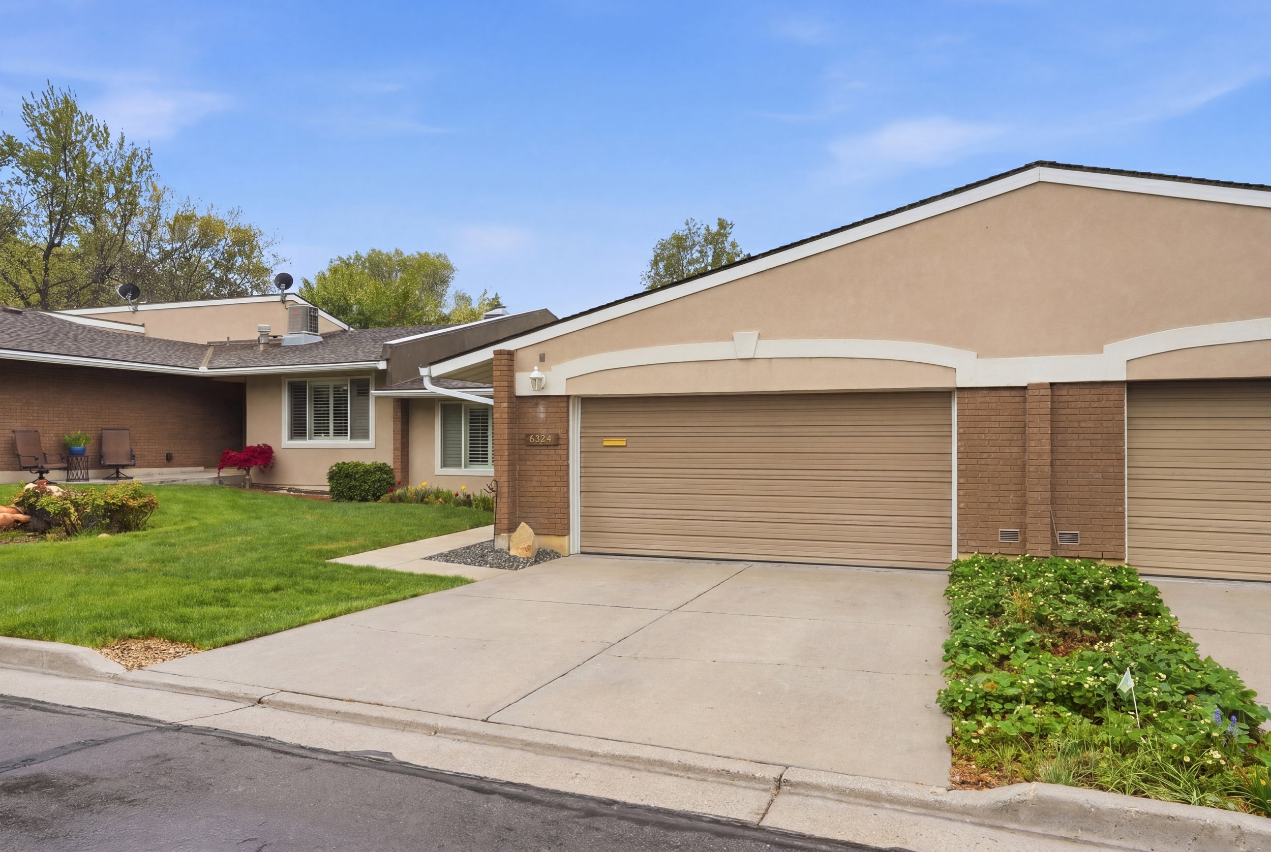 View of front facade with driveway, stucco siding, an attached garage, and brick siding