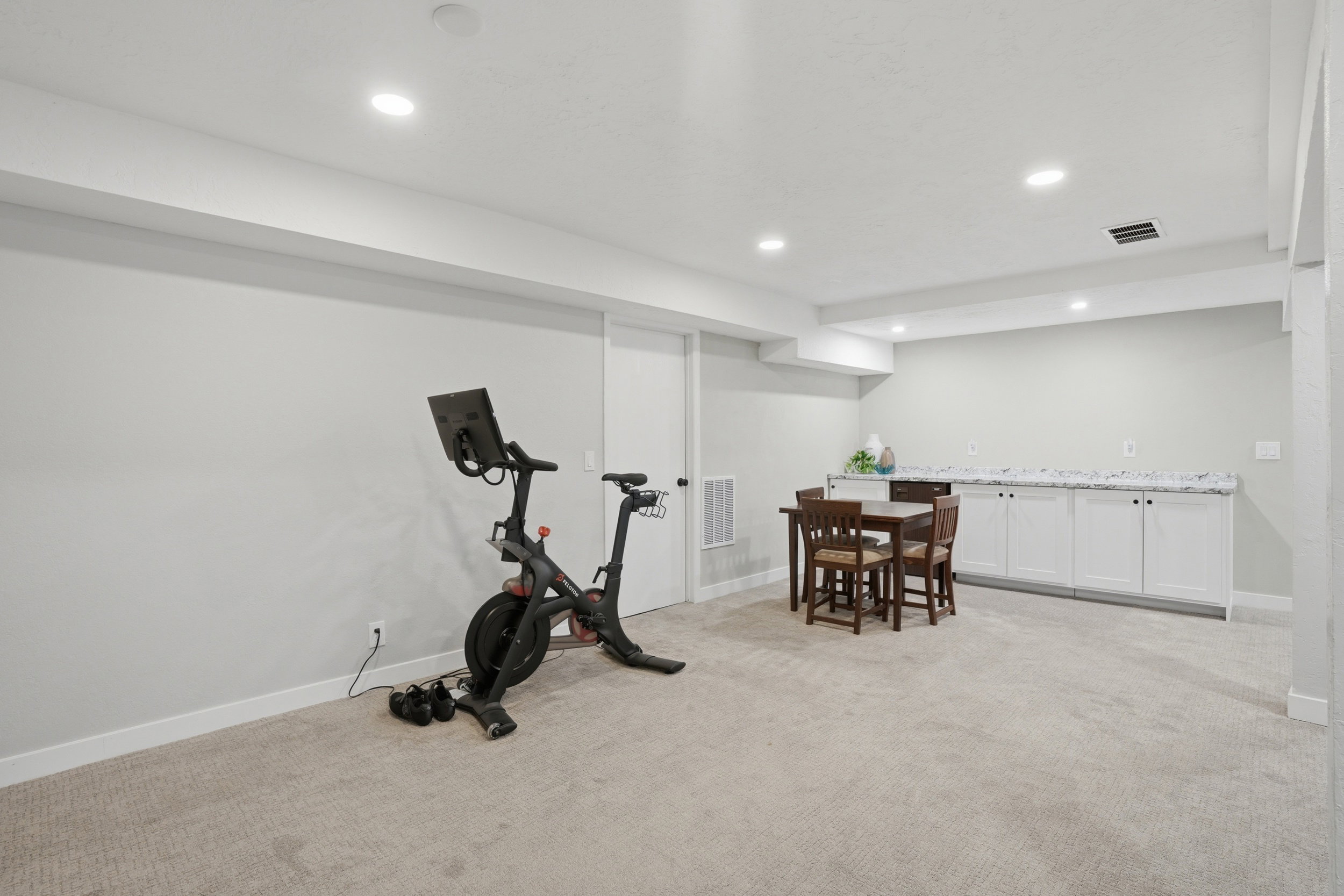 Exercise area with light carpet, recessed lighting, and wet bar