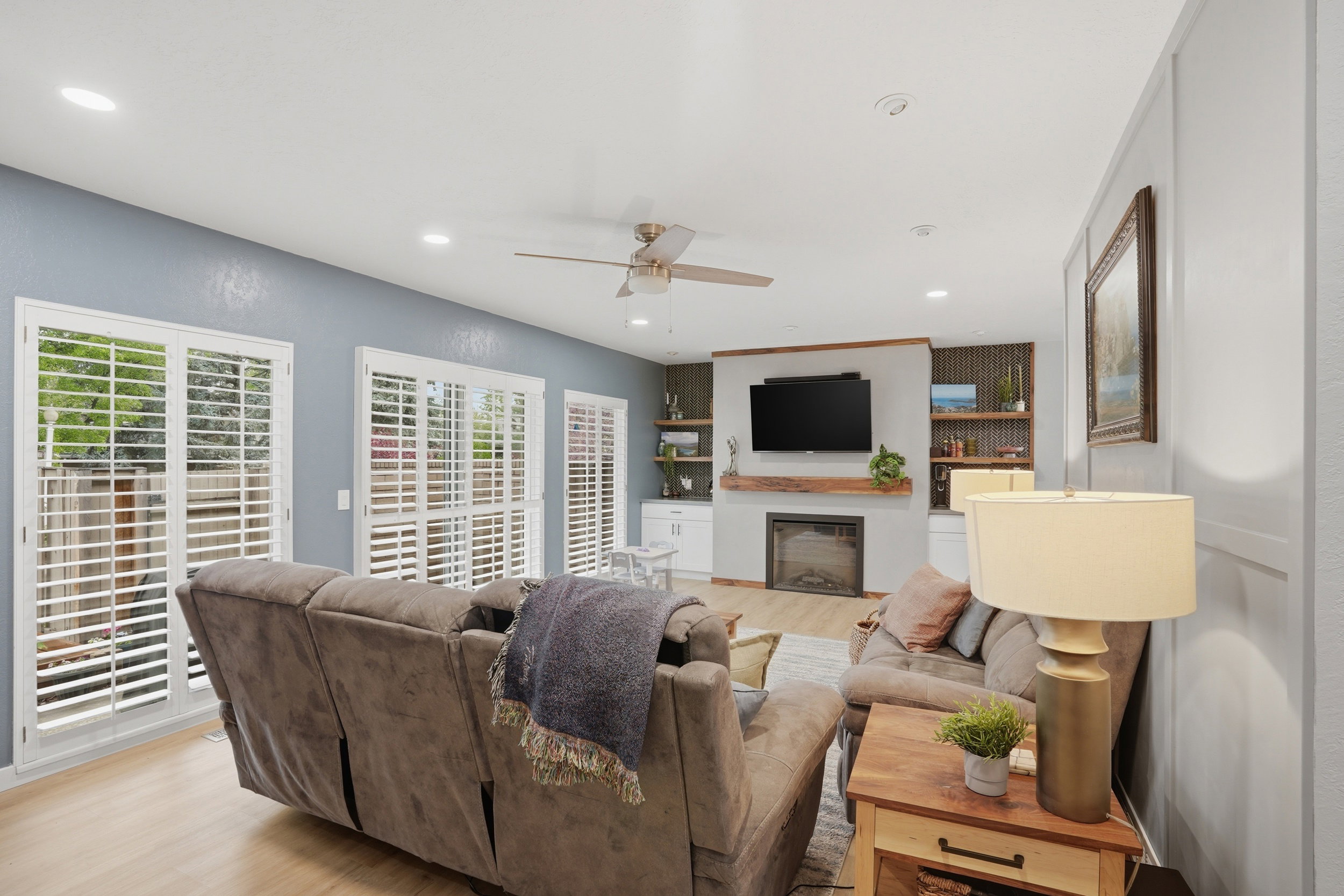 Living room featuring light wood-style flooring, ceiling fan, recessed lighting, and a fireplace