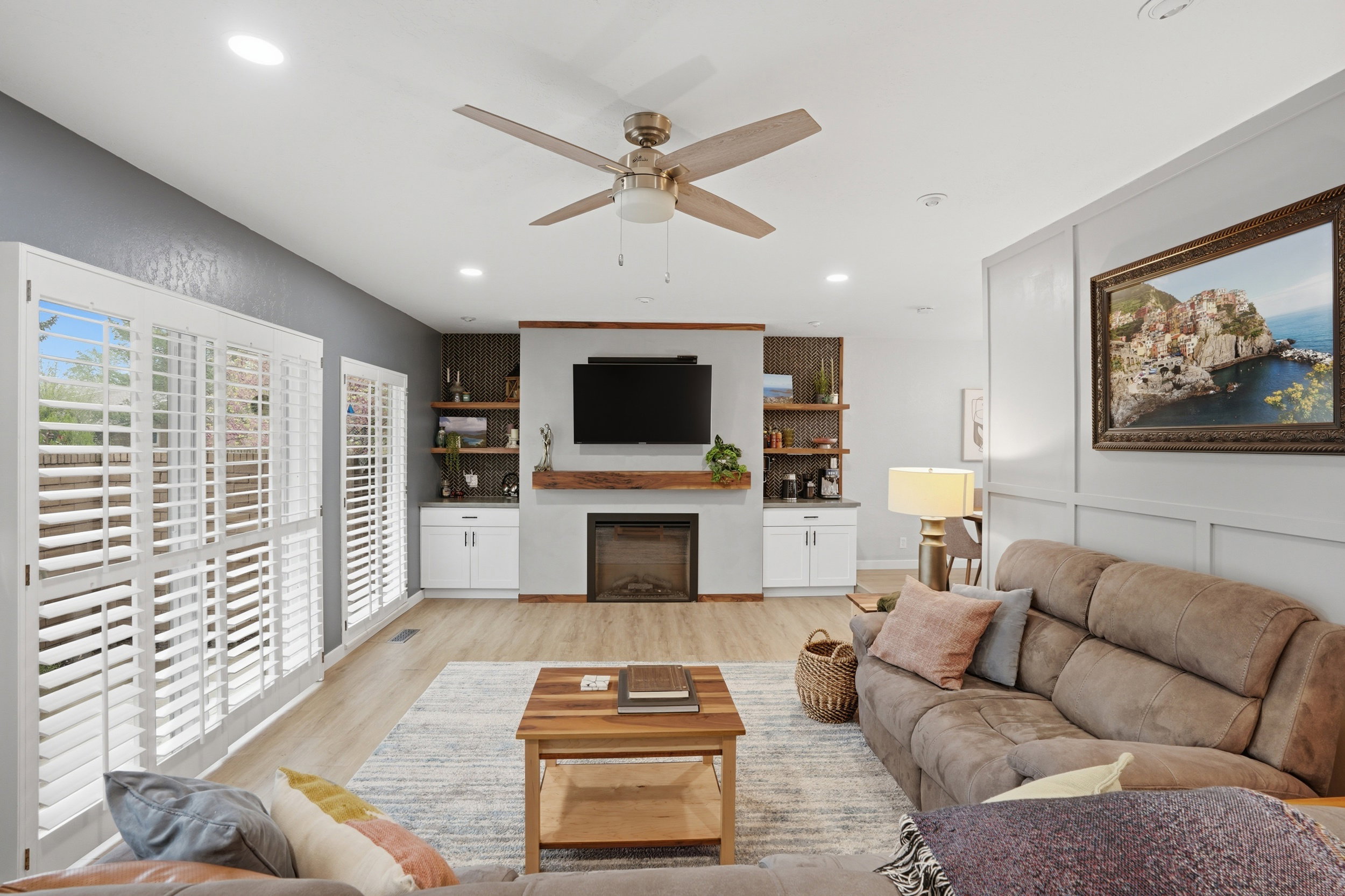 Living room featuring ceiling fan, light wood-style flooring, a glass covered fireplace, and recessed lighting