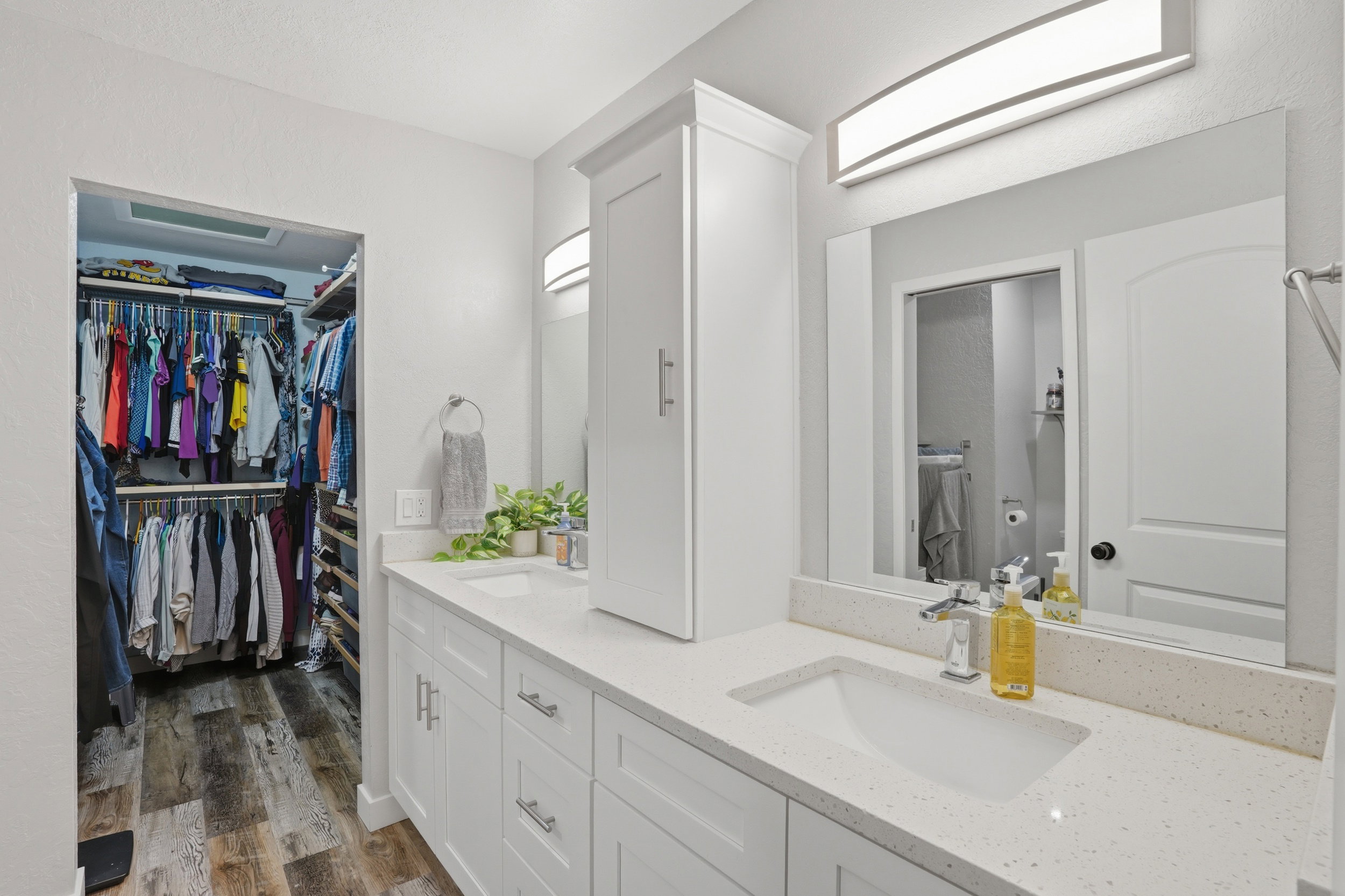Full bathroom featuring double vanity, dark wood-style floors, and a walk in closet