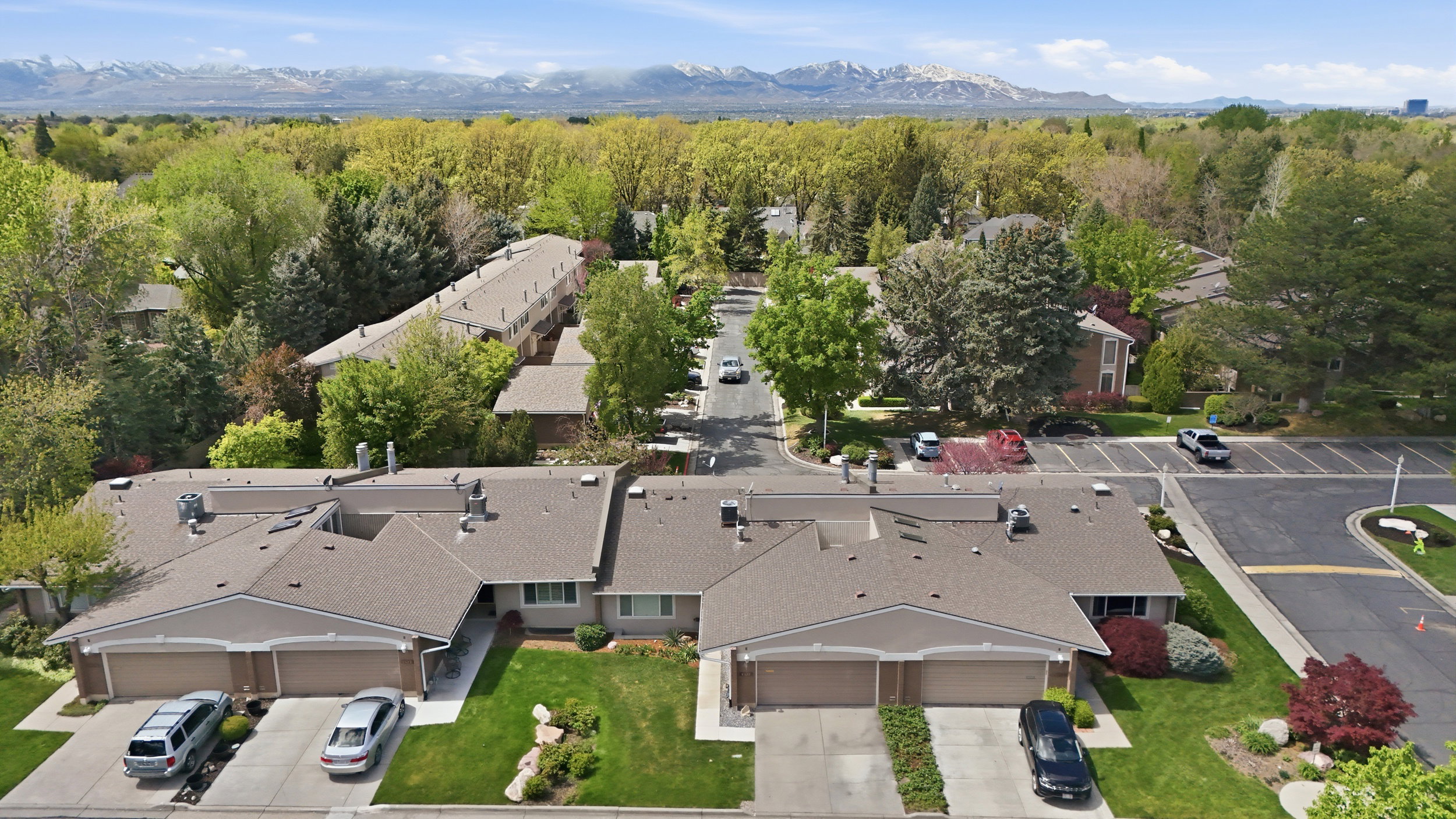 Aerial view of residential area featuring a mountain backdrop and a heavily wooded area