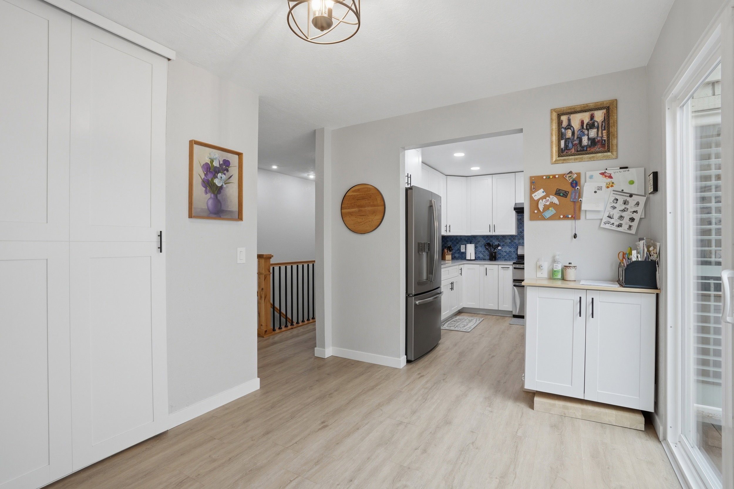 Kitchen with light countertops, white cabinetry, stainless steel fridge, light wood-style flooring, and decorative backsplash