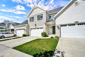 Traditional home with driveway, stone siding, stucco siding, a garage, and a shingled roof