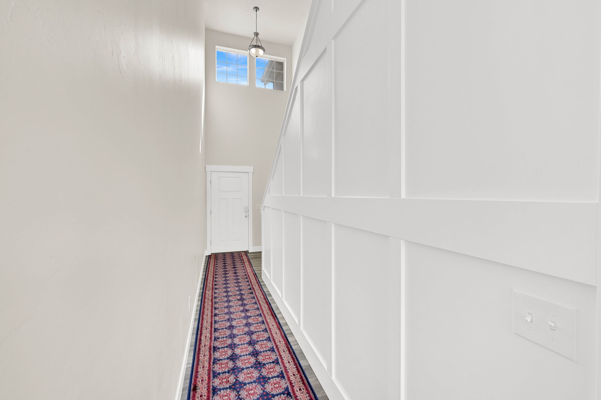 Hall with wood finished floors and a high ceiling