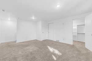 Unfurnished bedroom with a walk in closet and light colored carpet