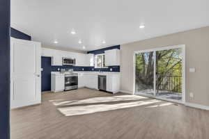 Kitchen with light countertops, stainless steel appliances, light wood-type flooring, white cabinetry, and recessed lighting