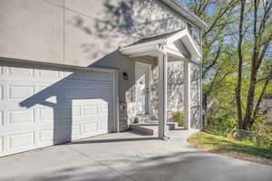 Doorway to property with driveway, stucco siding, and a shingled roof