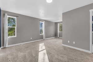 Empty room with light colored carpet and plenty of natural light
