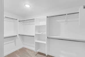 Walk in closet featuring light colored carpet