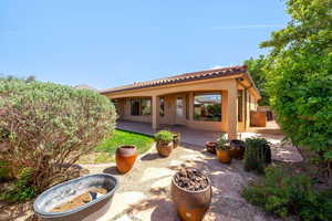 Rear view of property featuring a patio area, stucco siding, and a tiled roof