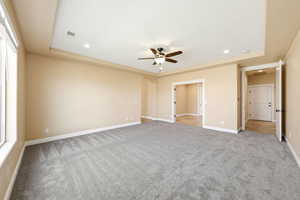 Unfurnished bedroom featuring arched walkways, a ceiling fan, recessed lighting, a raised ceiling, and light colored carpet