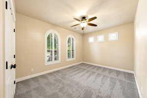 Spare room with light carpet, a ceiling fan, and a textured ceiling