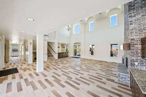 Unfurnished living room with a brick fireplace, a high ceiling, and recessed lighting