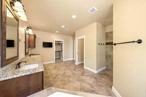 Full bath featuring double vanity, a walk in closet, and recessed lighting