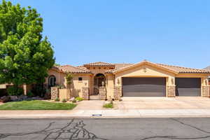 Mediterranean / spanish-style home featuring stone siding, stucco siding, a garage, a gate, and driveway