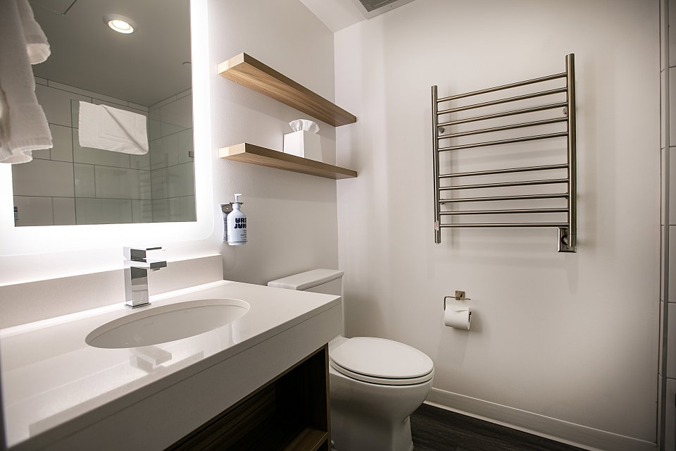 Bathroom featuring a towel warmer, radiator heating unit, vanity, dark wood-type flooring, and recessed lighting