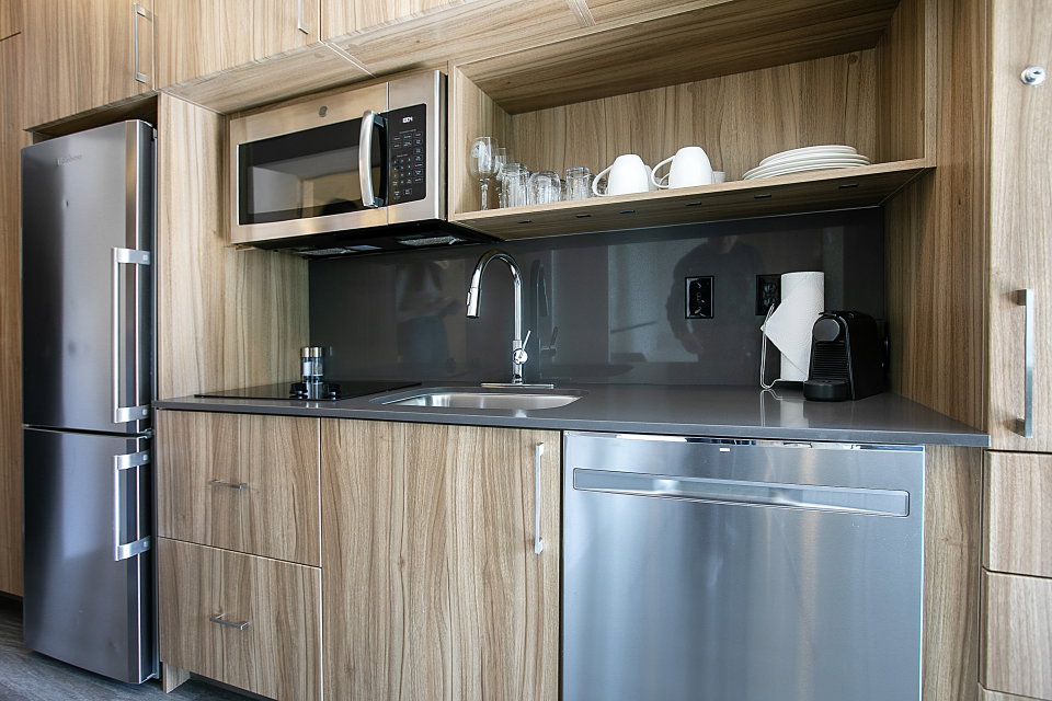 Kitchen with stainless steel appliances, modern cabinets, open shelves, and dark stone counters