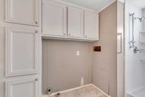 Laundry room featuring light marble finish flooring, hookup for a washing machine, and cabinet space