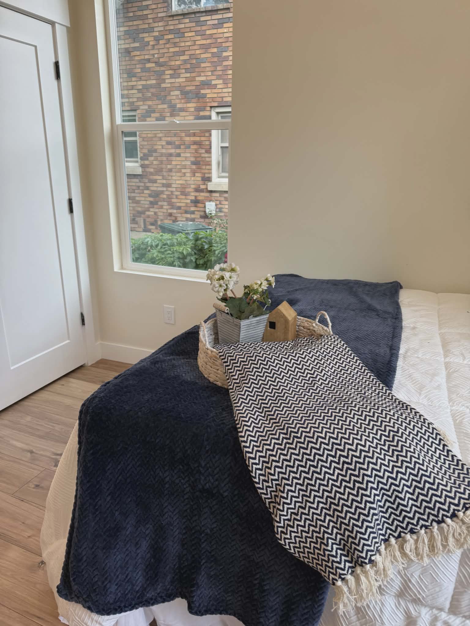 Bedroom featuring light wood-finish flooring, a white interior door with black hardware, and an expansive window