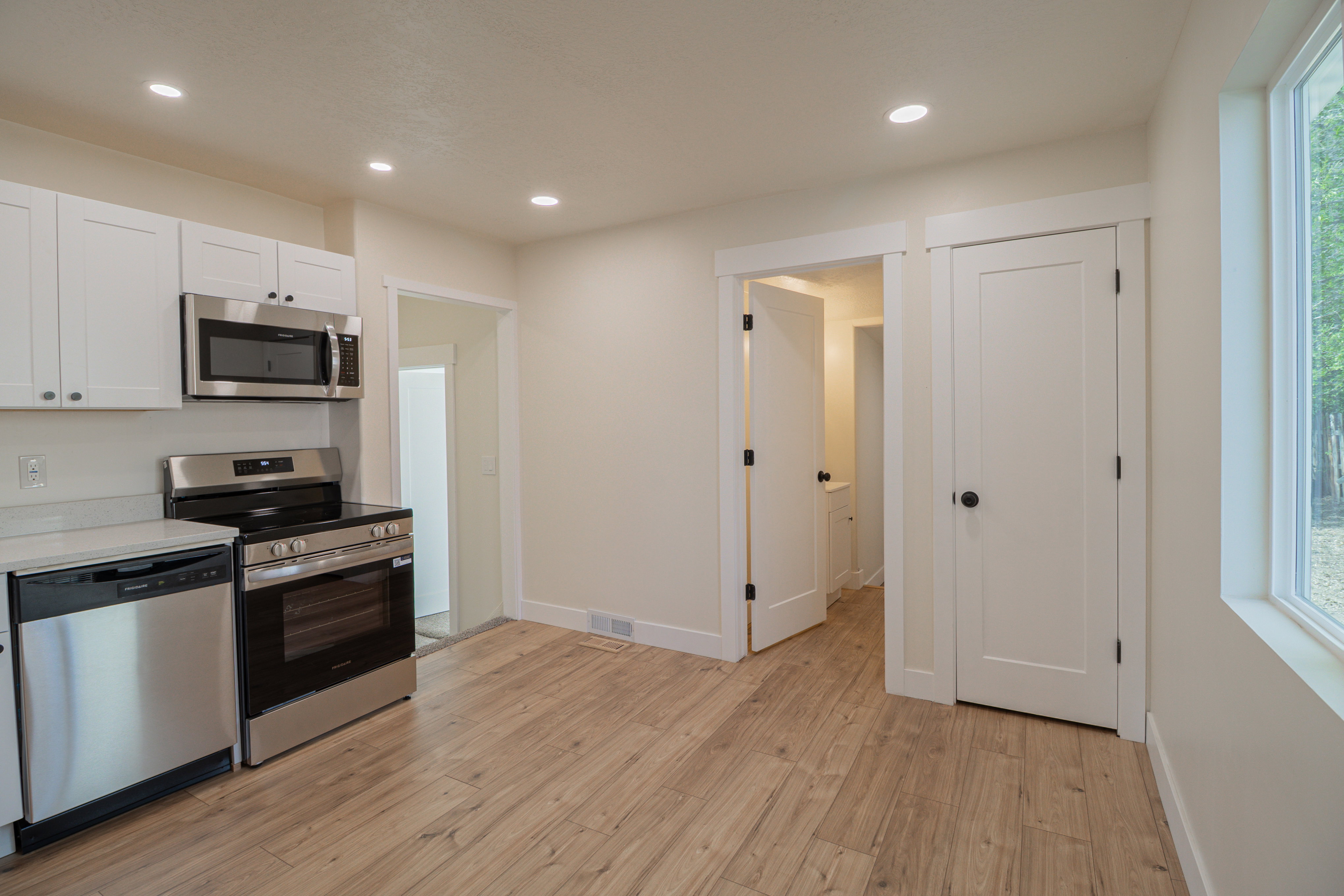 Kitchen featuring stainless steel appliances, light wood finished floors, white cabinets, recessed lighting, and light stone counters