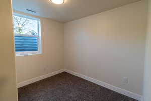 Spare room with baseboards and dark colored carpet