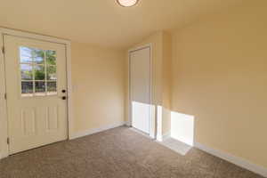 Doorway to outside featuring carpet floors and vaulted ceiling