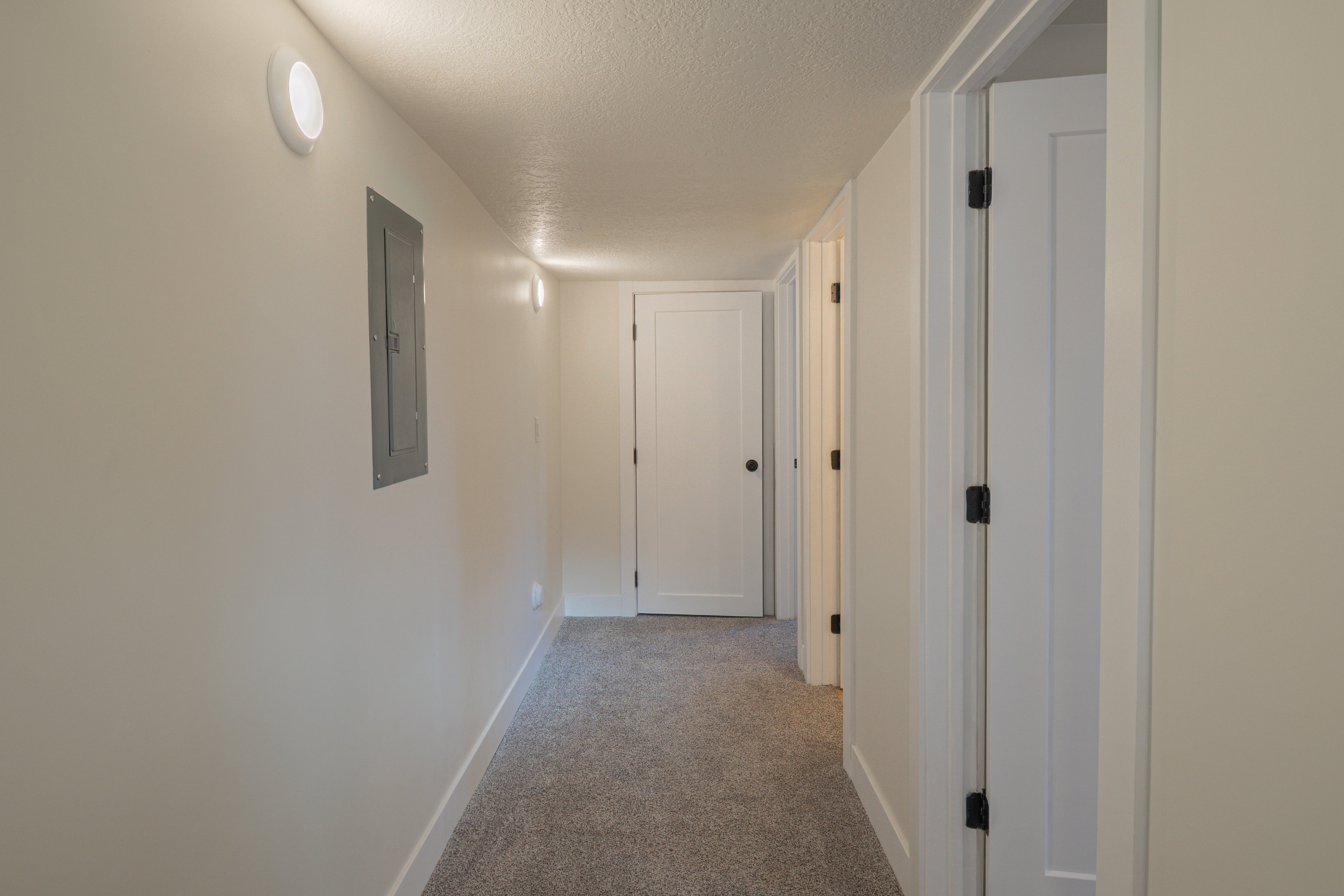 Corridor featuring a textured ceiling, light carpet, and electric panel