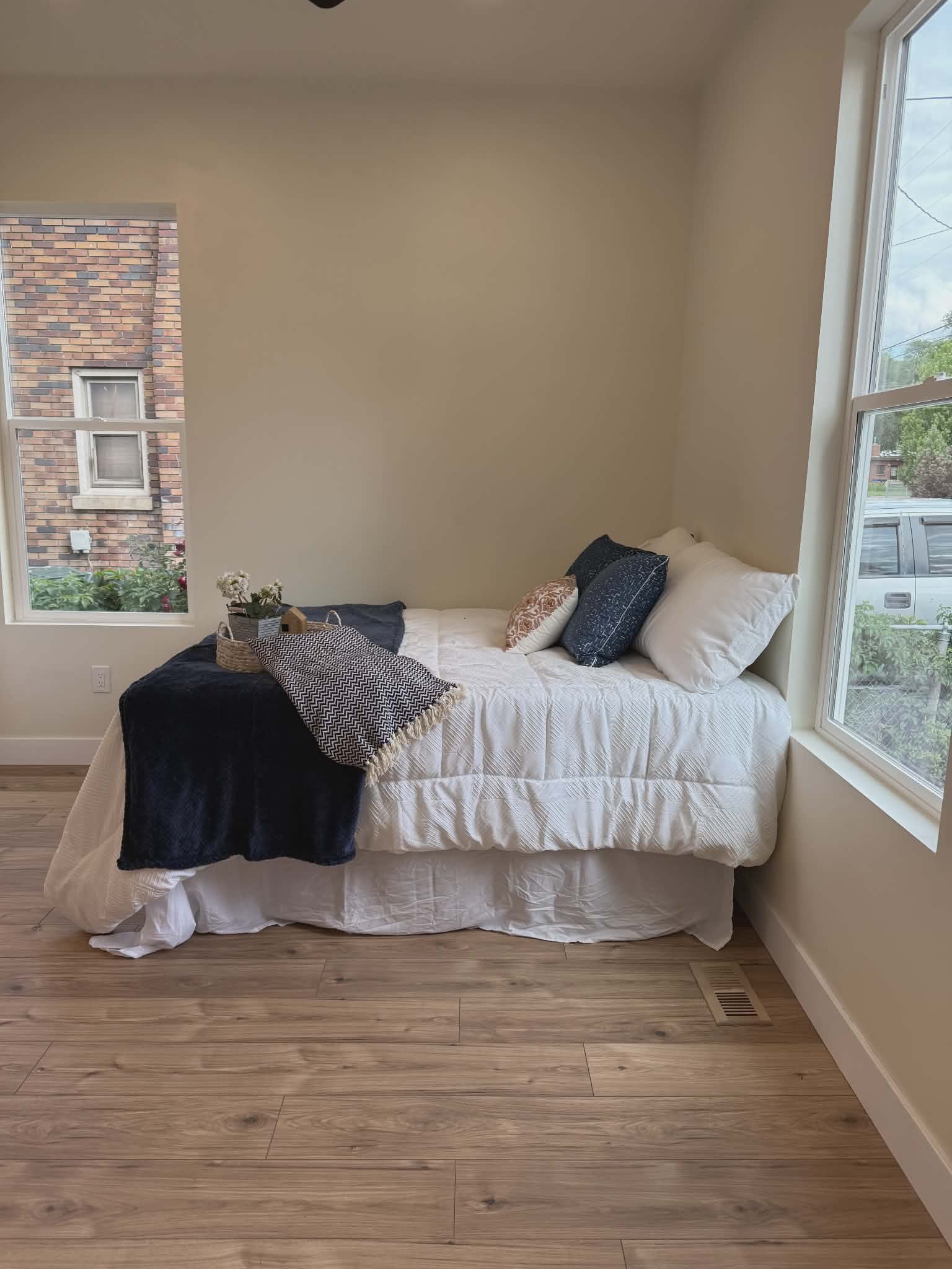 Room with wood-finish flooring, two window openings, light-toned wall paint, and white baseboards