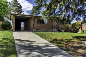 View of front of property featuring a front lawn, an attached carport, driveway, and brick siding