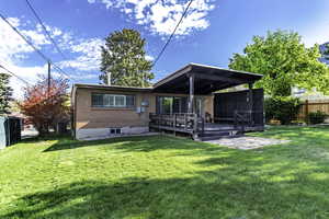 Back of property with a fenced backyard, a wooden deck, and brick siding