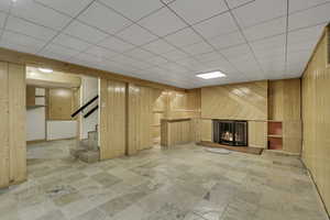 Finished below grade area with a fireplace, wooden walls, and a paneled ceiling