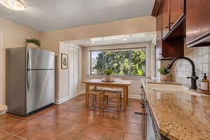 Kitchen featuring stainless steel appliances, light stone countertops, dark tile patterned flooring, recessed lighting, and decorative backsplash