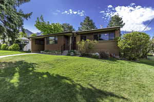 Single story home featuring a front yard, brick siding, and a mountain view
