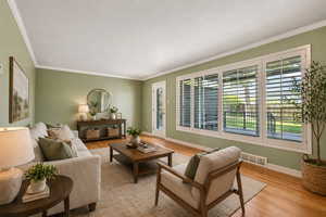 Living room with light wood-style flooring and ornamental molding
