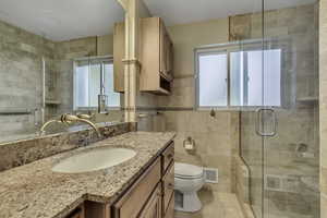 Bathroom featuring tile walls, vanity, a stall shower, and light tile patterned floors