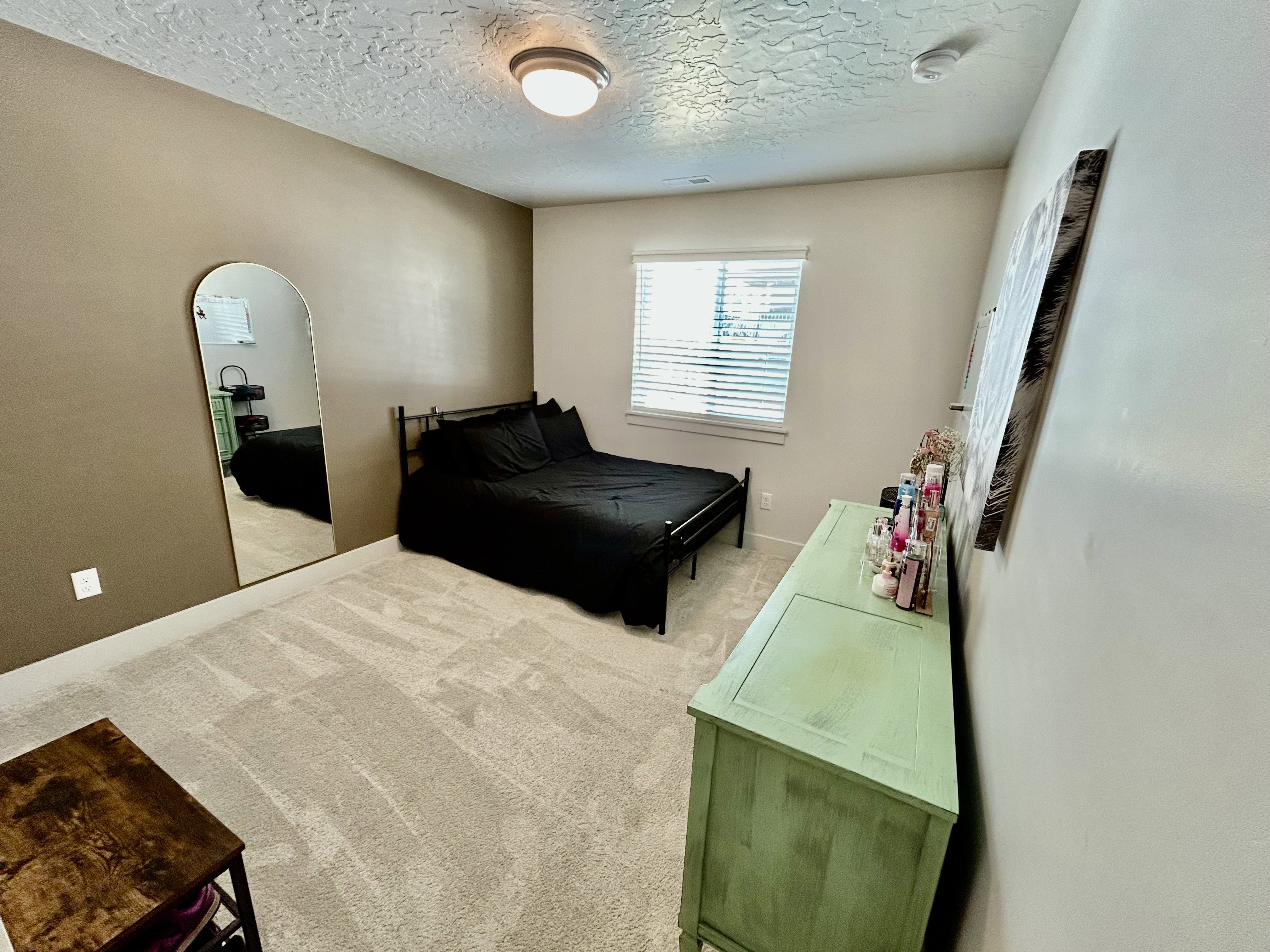 Bedroom with light carpet, arched walkways, and a textured ceiling