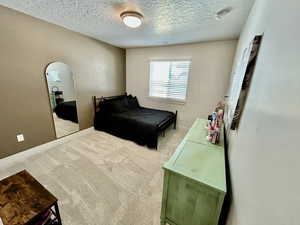 Bedroom with light carpet, arched walkways, and a textured ceiling