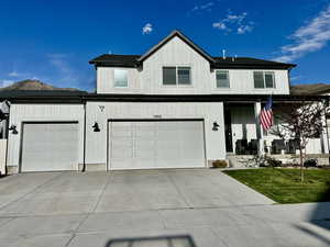 Modern inspired farmhouse featuring a porch, driveway, and a 3 car garage, with mountains behind