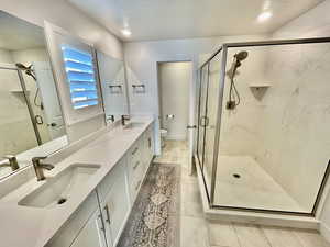 Bathroom with double vanity, a marble finish shower, and recessed lighting