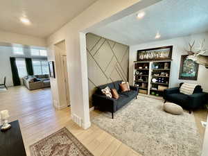 Living room featuring a textured ceiling, light wood finished floors, and recessed lighting